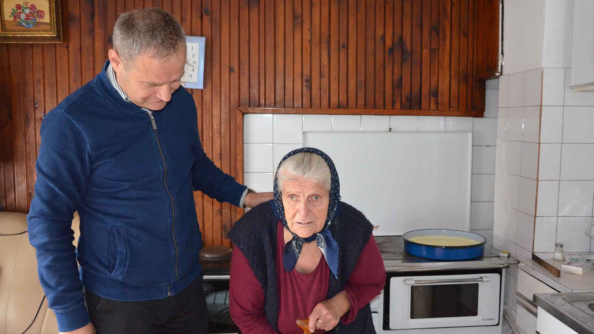 A Mission coordinator prays with an elderly lady.