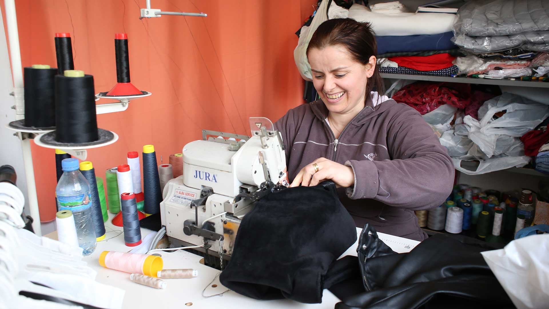 A lady sits at a sewing machine.